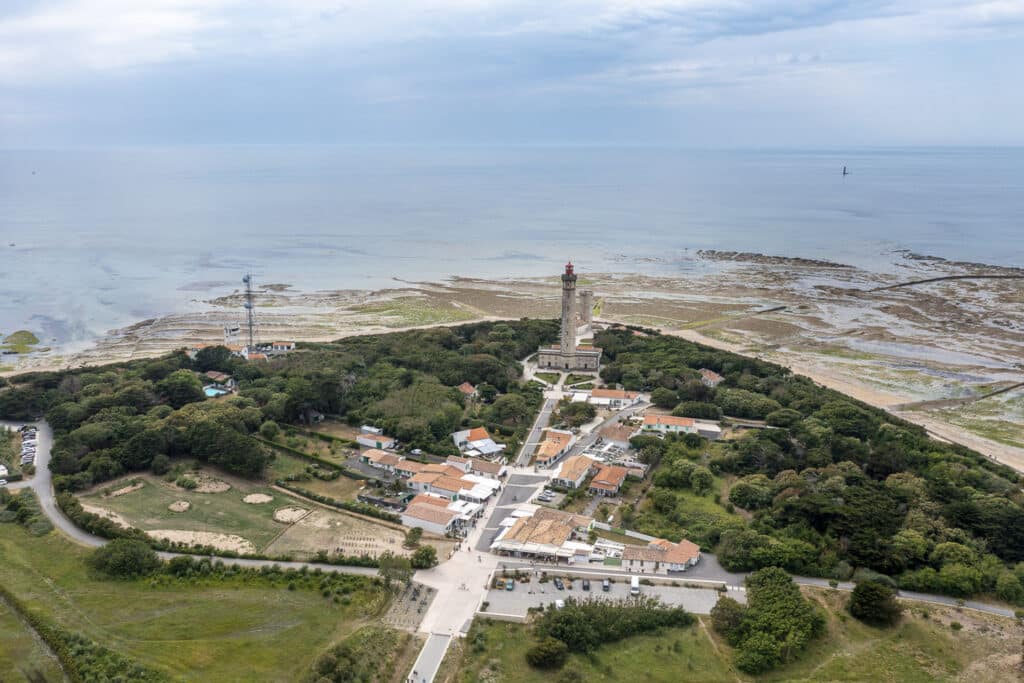 Phare et océan depuis les airs, île verdoyante.