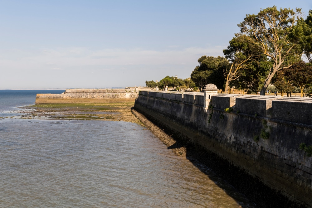 Rempart historique au bord de la mer, ciel dégagé.