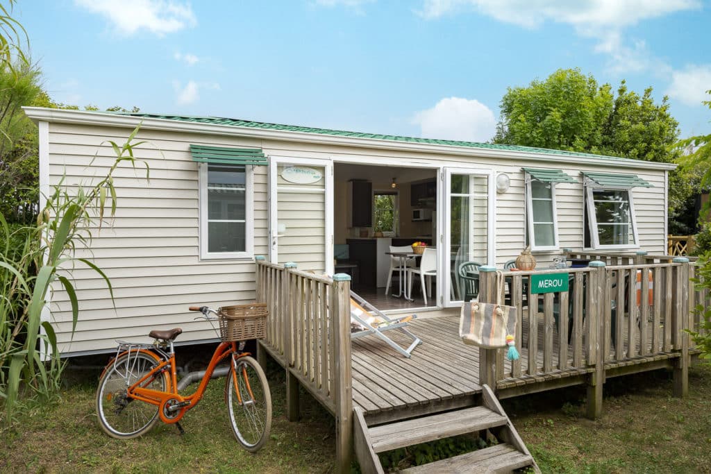 Mobil-home avec terrasse en bois et vélo orange.