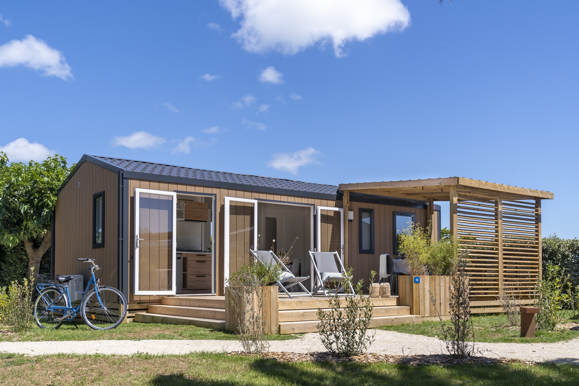 Mobil-home moderne avec terrasse en bois et vélo.