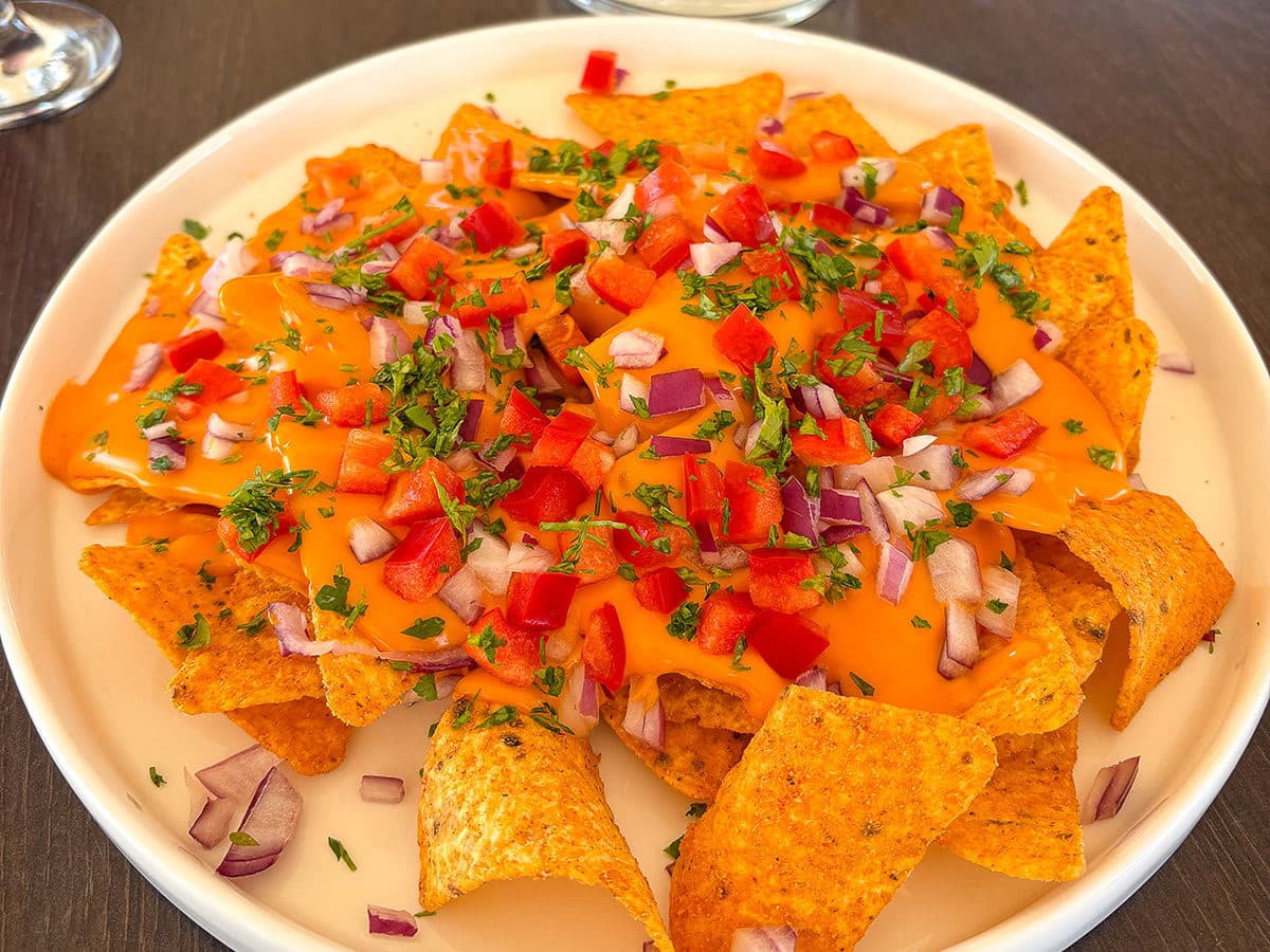 Nachos au fromage fondu, oignons et poivrons rouges.