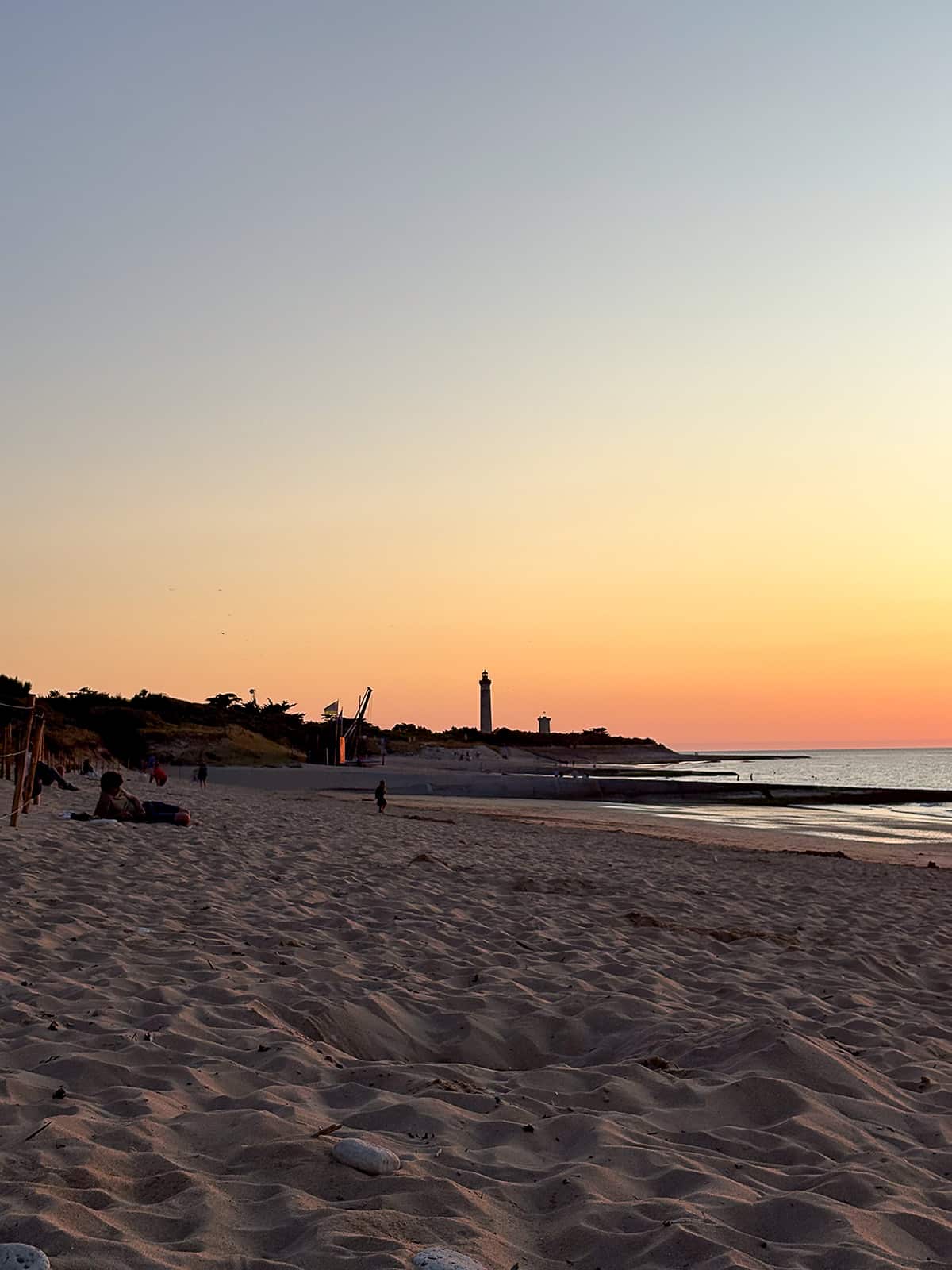 Plage au coucher du soleil avec phare.