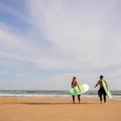 Deux personnes avec des planches de surf qui se dirigent vers l'océan