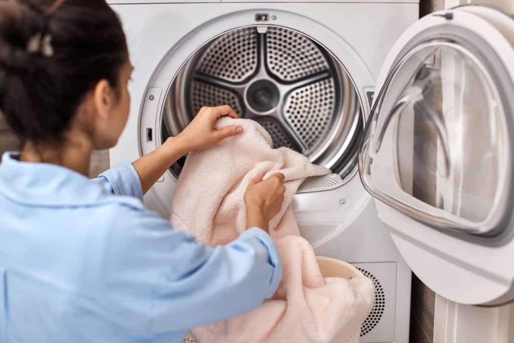 Personne charge une machine à laver avec serviettes.