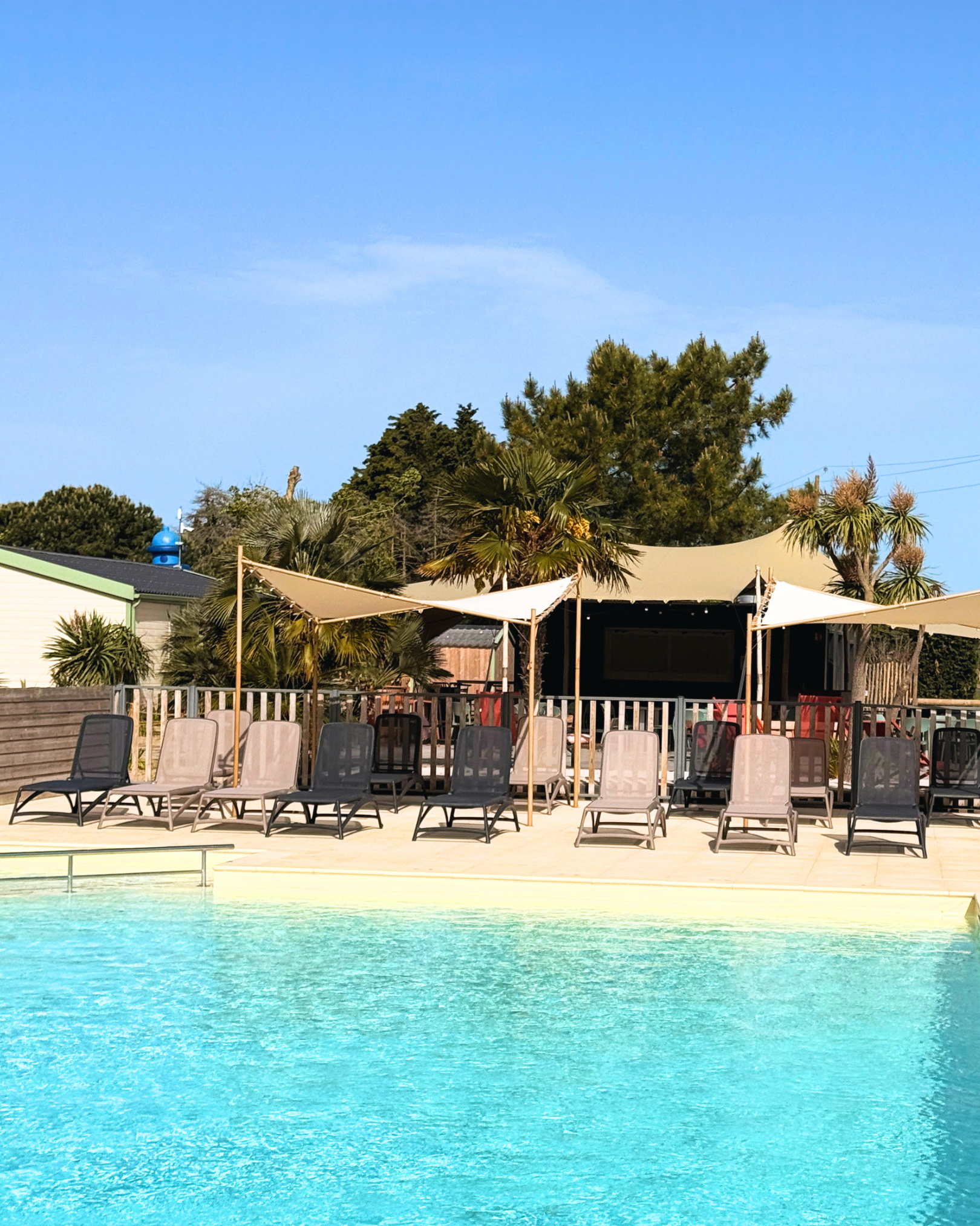 Piscine extérieure avec chaises longues et parasols.