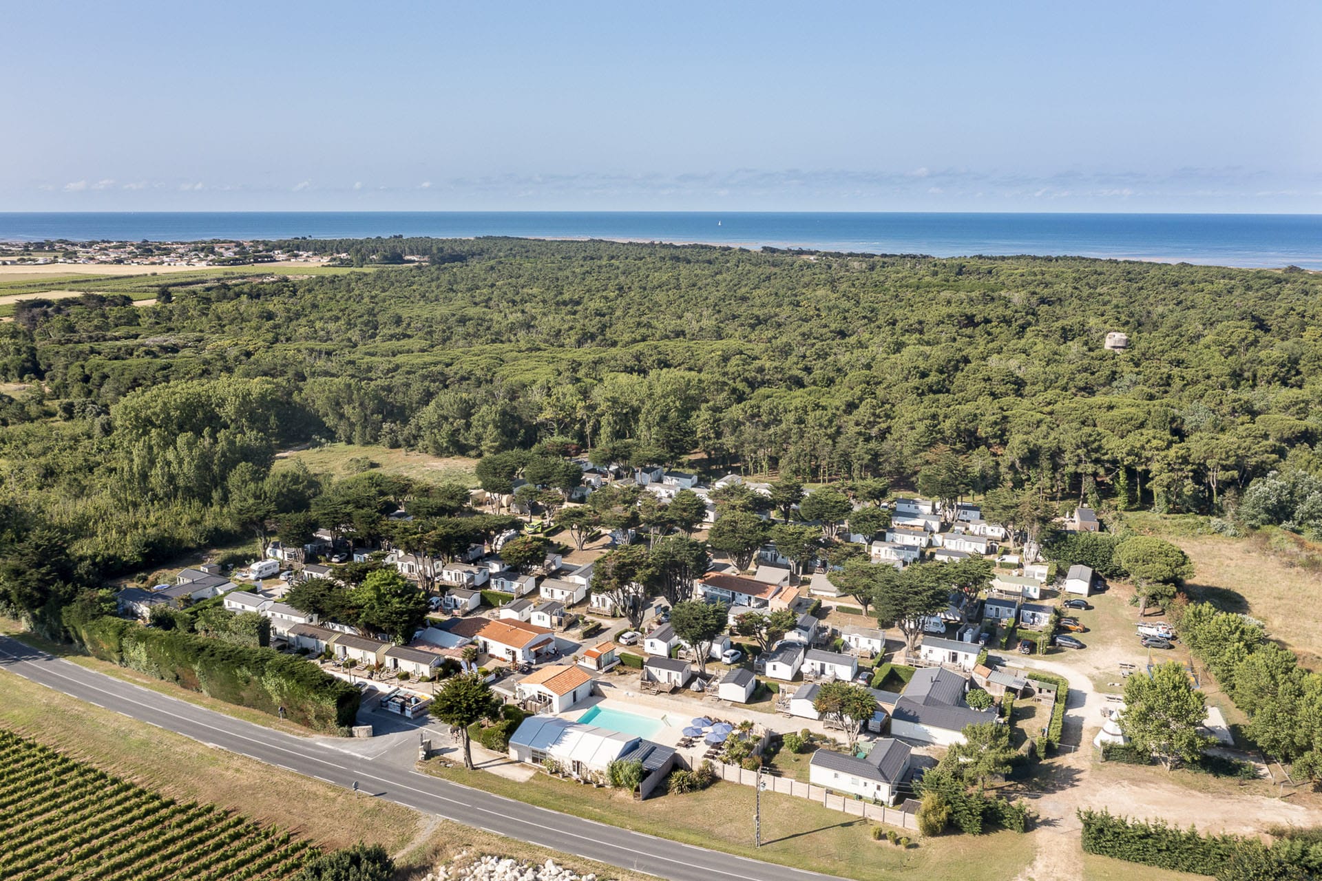 Vue aérienne d'un camping en forêt proche de la mer.