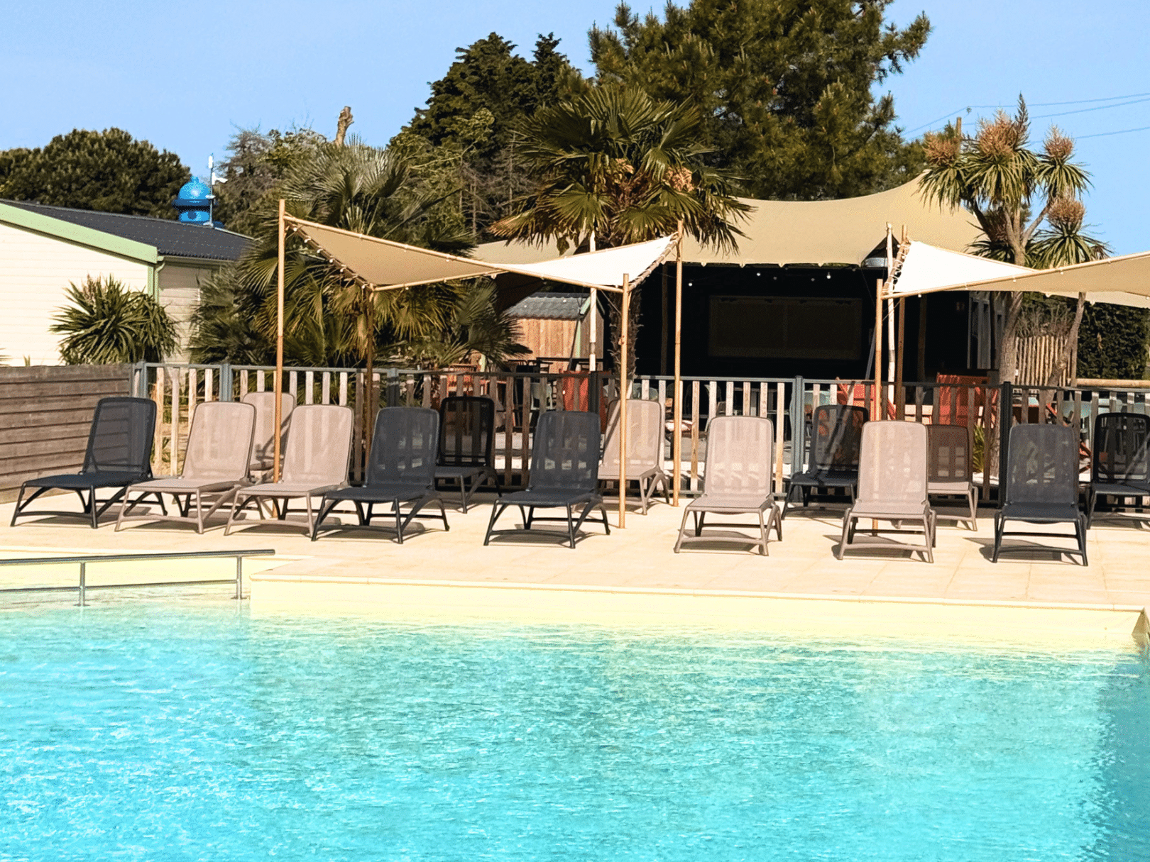 Piscine extérieure avec chaises longues et parasols.